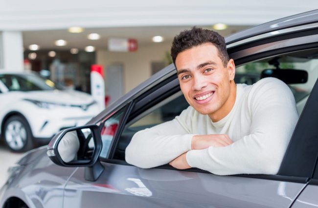 Man smiling in car illustrates blog "OEM vs Aftermarket Parts: What Is the Difference?"