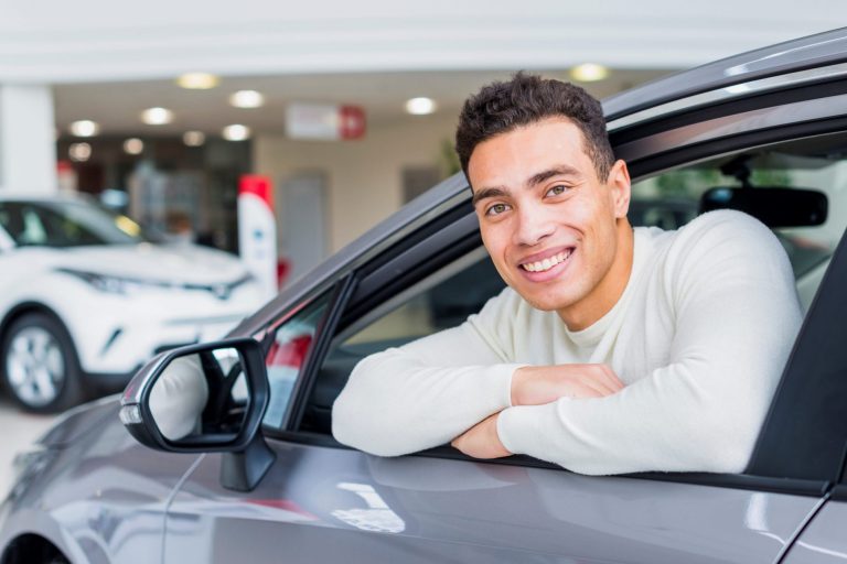Man smiling in car illustrates blog "OEM vs Aftermarket Parts: What Is the Difference?"