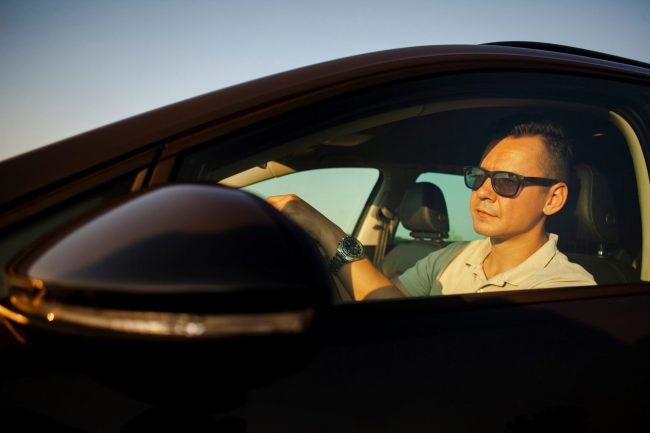 Man driving wearing sunglasses illustrates blog "How To Keep Your Car Cool this Summer"