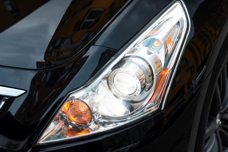 Closeup of headlights and high beams of white car.