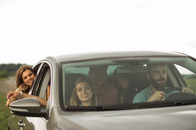 side-view-mirror Group of people in car with side-view mirror in the foreground.