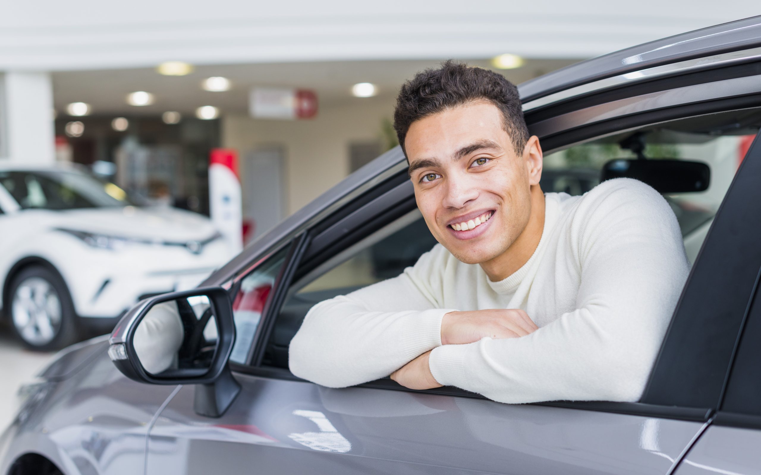 Man smiling from car illustrates blog "4 New Year's Resolutions To Keep Your Car's Body in Top Shape"