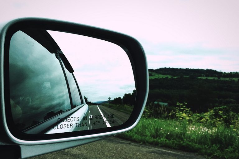 Side view mirror reflecting road illustrates blog "Why Does My Side View Mirror Shake?"